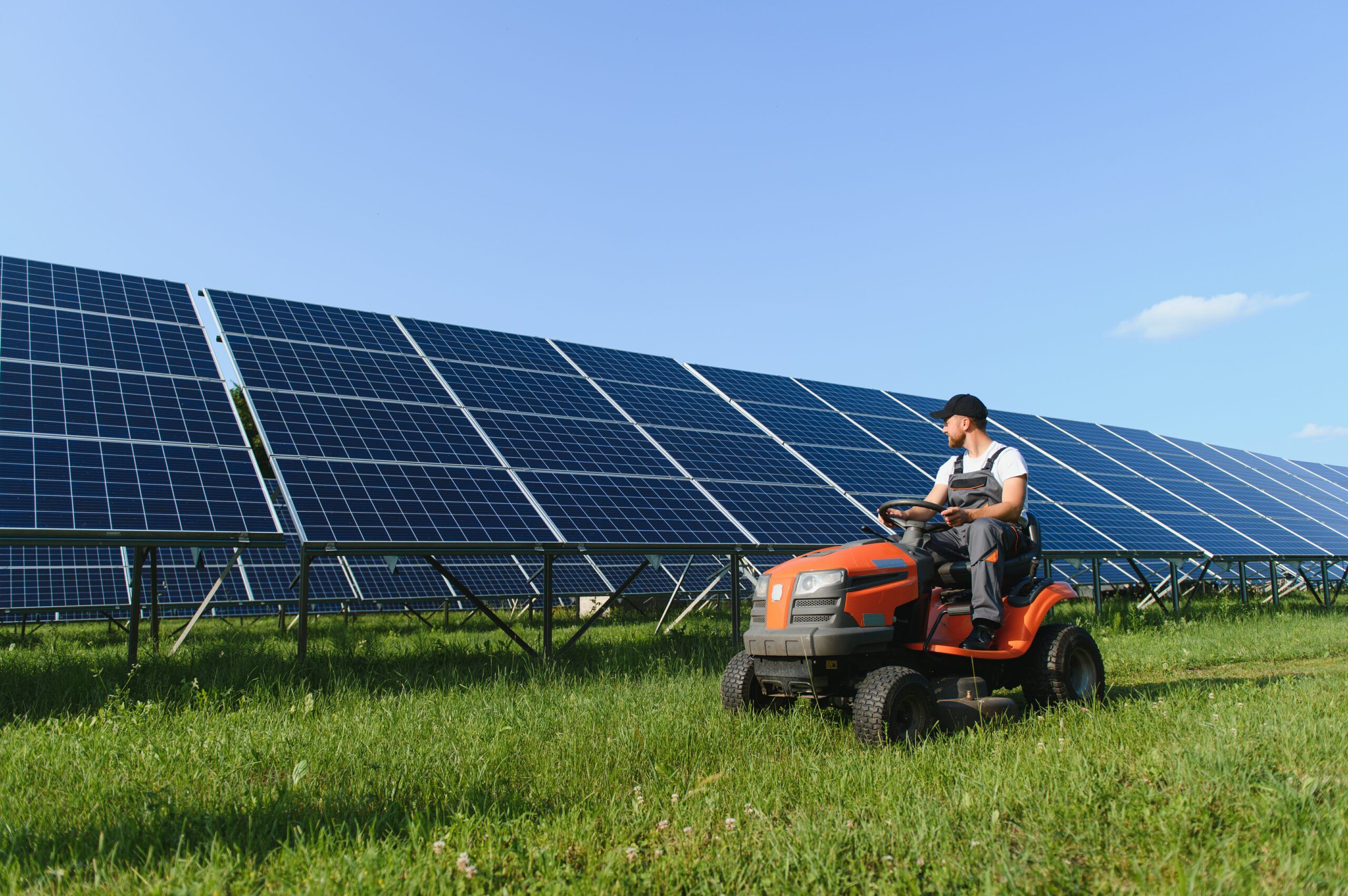 Man driving a lawnmower near solar panels, representing solar energy use